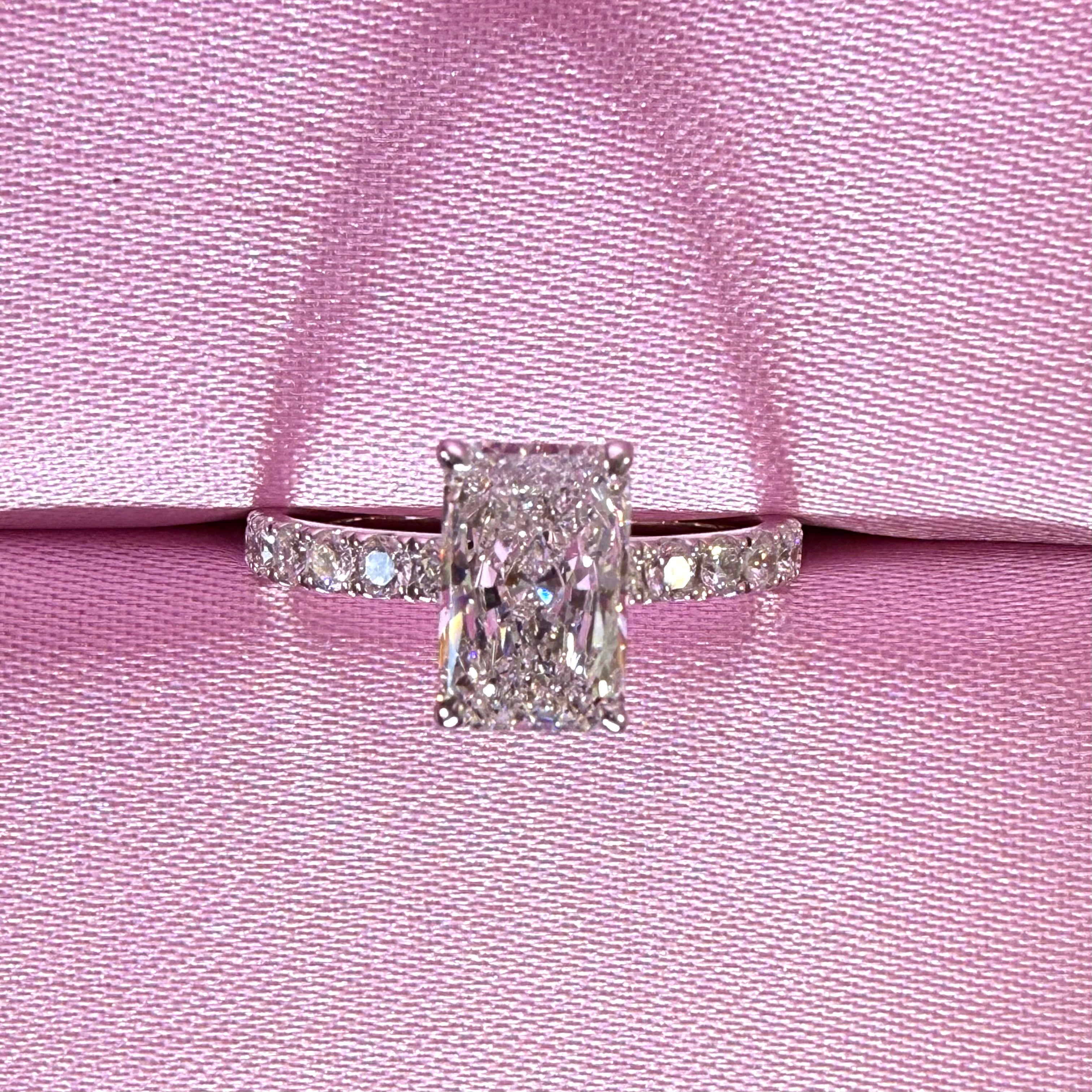 Radiant-cut diamond pavé ring in white gold displayed in a pink ring box.
