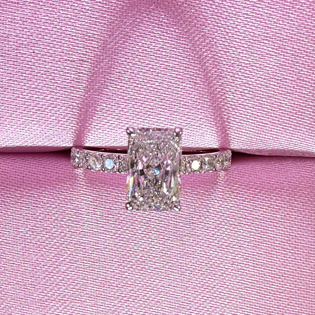Radiant-cut diamond pavé ring in white gold displayed in a pink ring box.