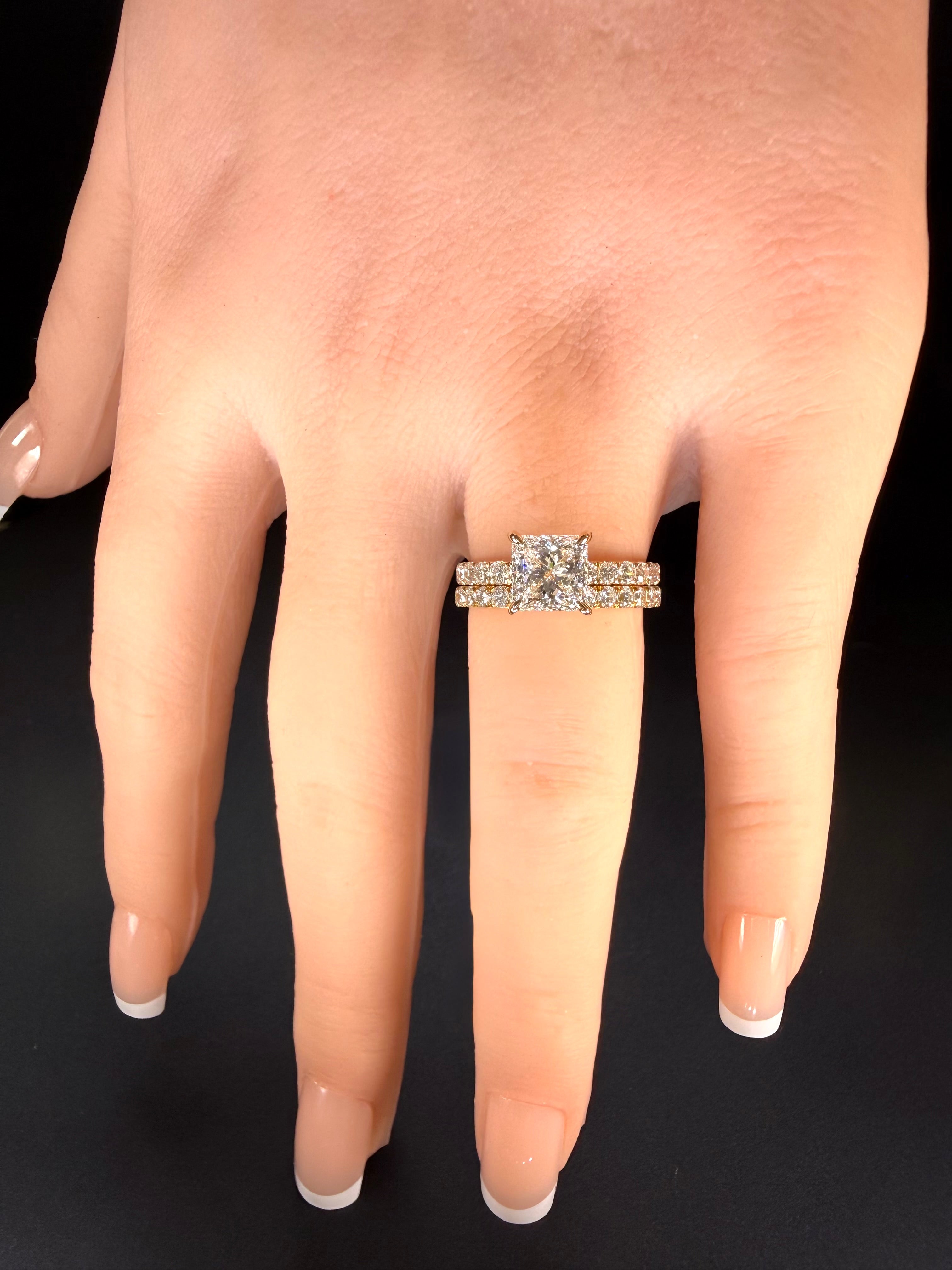 Princess-cut diamond pavé ring in yellow gold worn with one diamond-set band on a hand.