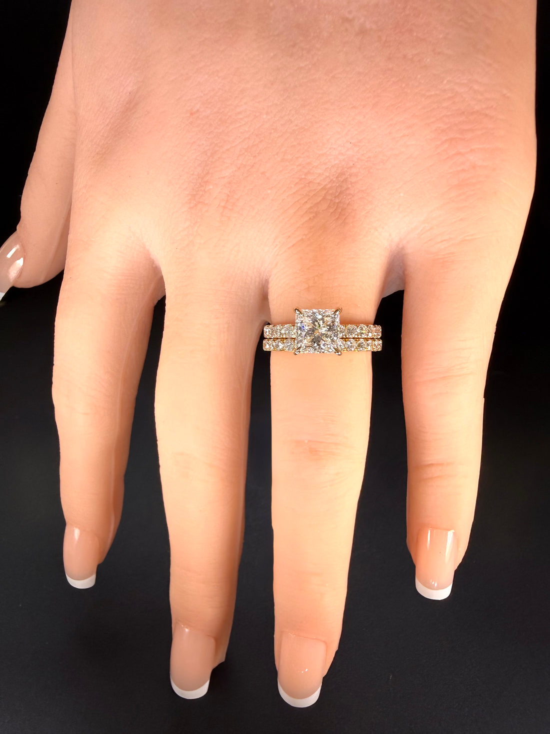 Princess-cut diamond pavé ring in yellow gold worn with one diamond-set band on a hand.