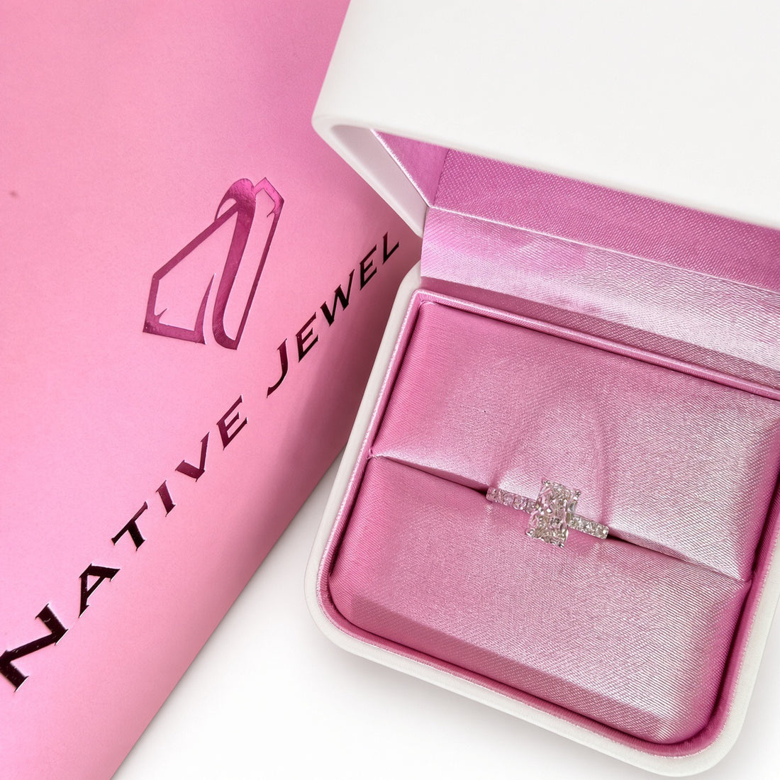Radiant-cut diamond pavé ring in white gold in a pink ring box beside Native Jewel packaging.