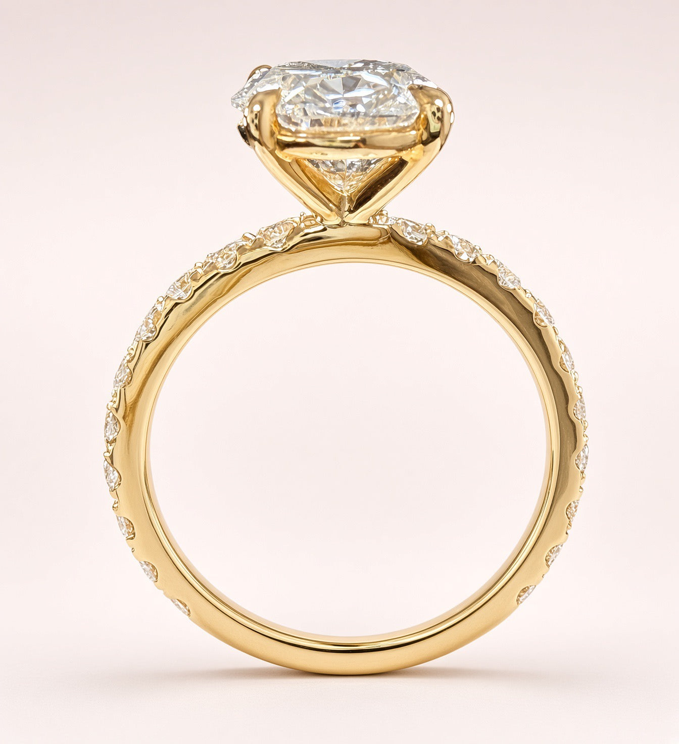 Opposite angled view of an oval diamond ring showing yellow-gold prongs and diamond-set shoulders.