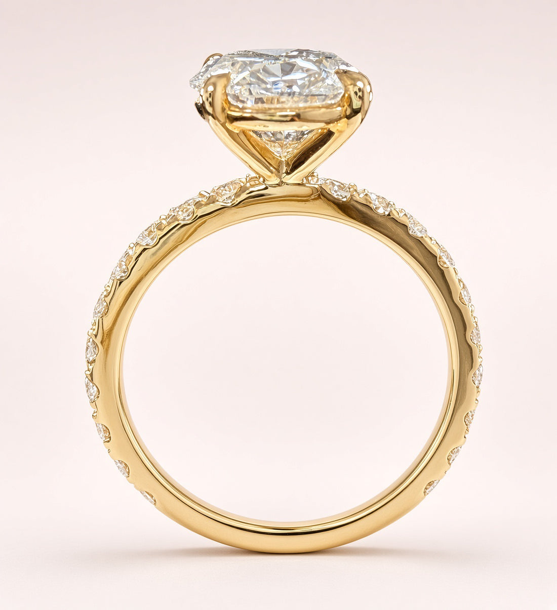 Opposite angled view of an oval diamond ring showing yellow-gold prongs and diamond-set shoulders.