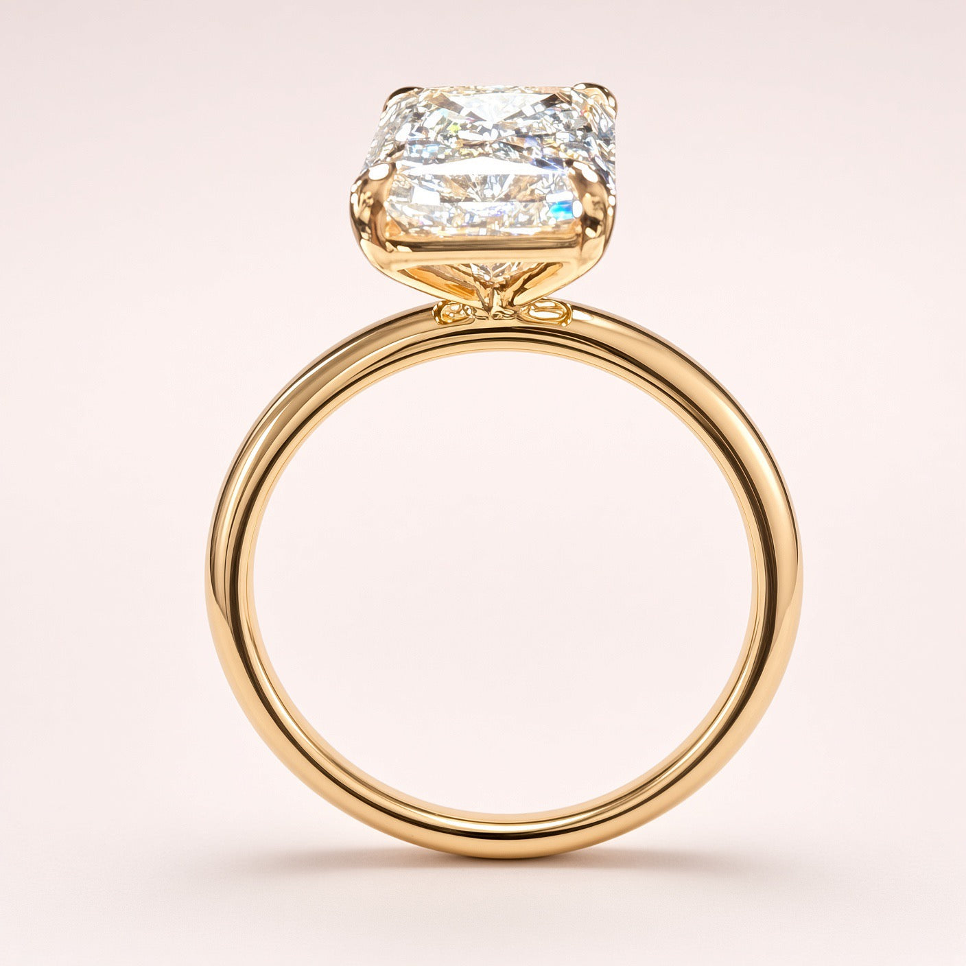 Side profile of a radiant-cut diamond solitaire showing its open yellow-gold basket and polished plain band.