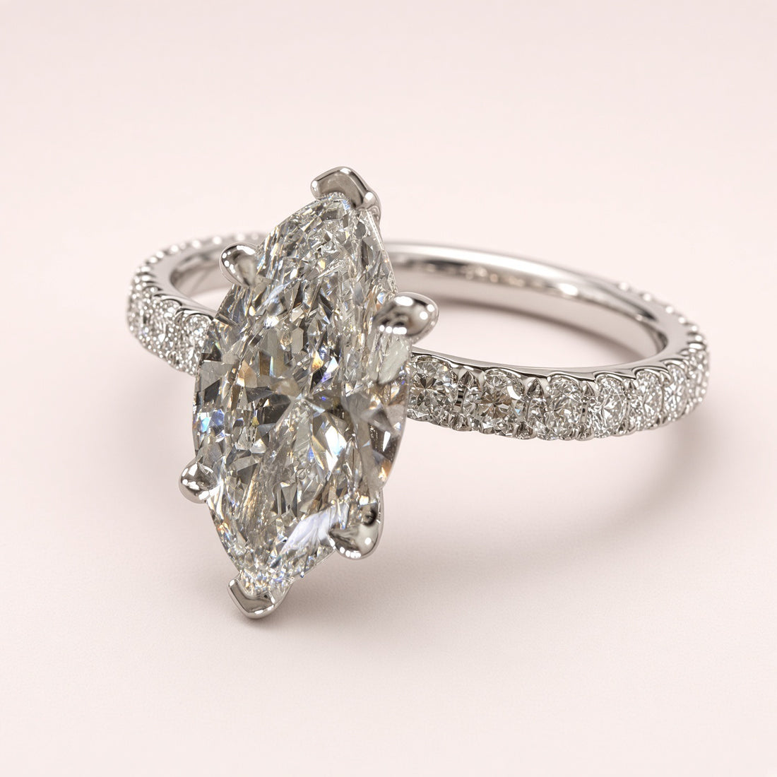 Opposite three-quarter view of a marquise diamond pavé ring in white gold on a pale pink background.