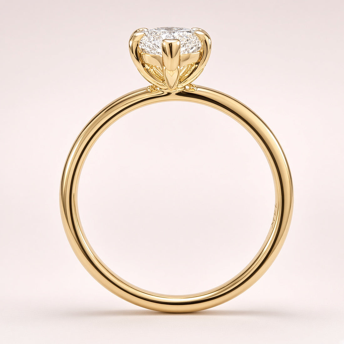 Side profile of a diamond solitaire showing an open yellow-gold basket and a plain polished band on pale pink.