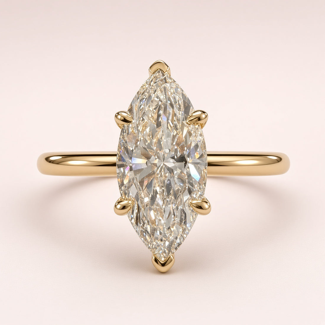 Front close-up of a marquise diamond solitaire with yellow-gold prongs protecting both tips and a plain band.