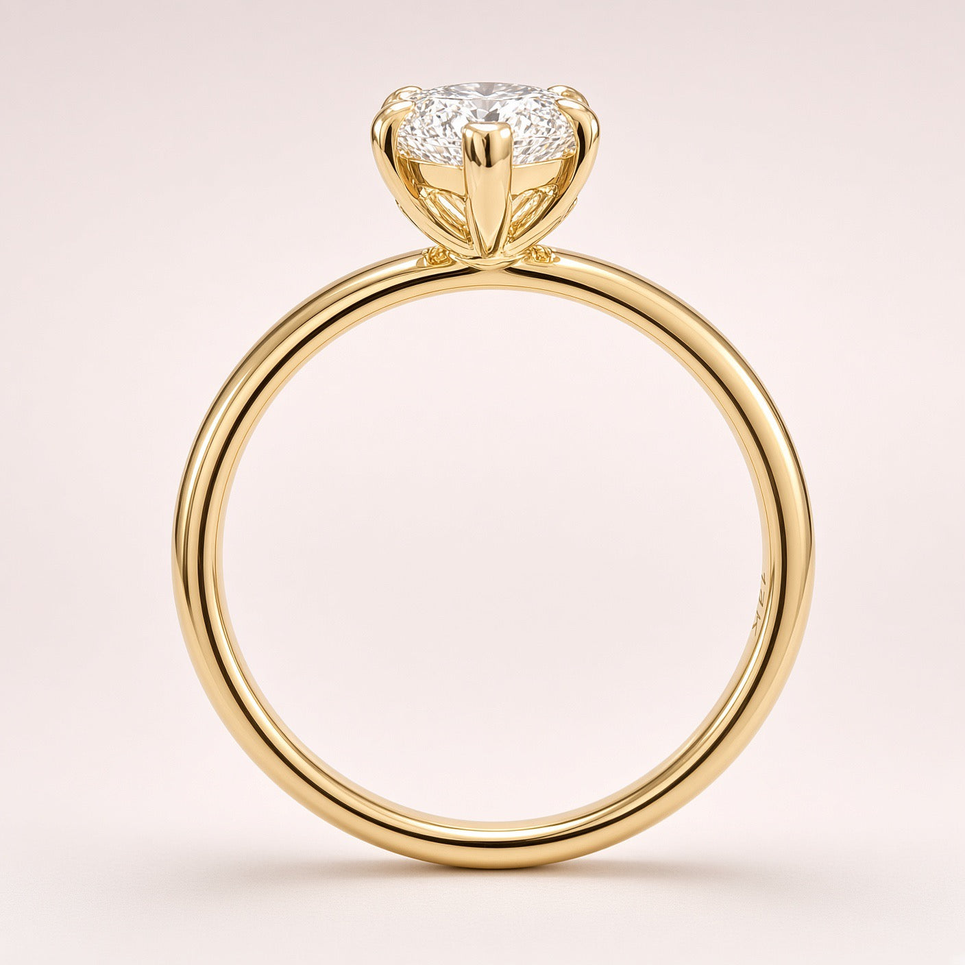 Side profile of a diamond solitaire showing an open yellow-gold basket and a plain polished band on pale pink.