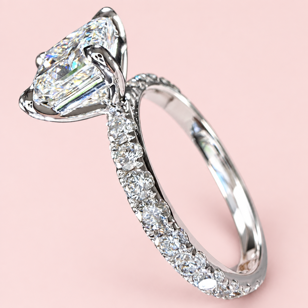 Side angle of a princess-cut diamond ring showing white-gold corner prongs and a pavé band on pink.