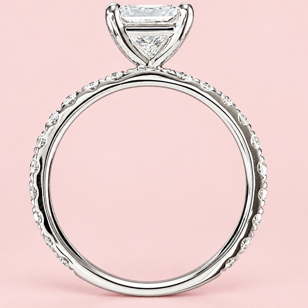 Side profile of a princess-cut diamond ring showing an open white-gold basket and diamond-set band on pink.