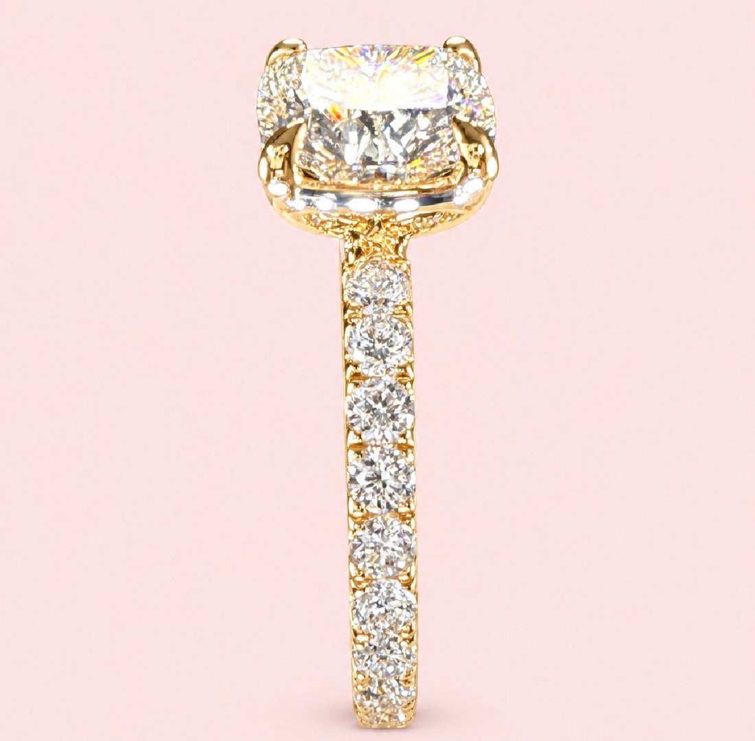 Side angle of a cushion-cut diamond ring in yellow gold showing the raised center setting and diamond-set band.