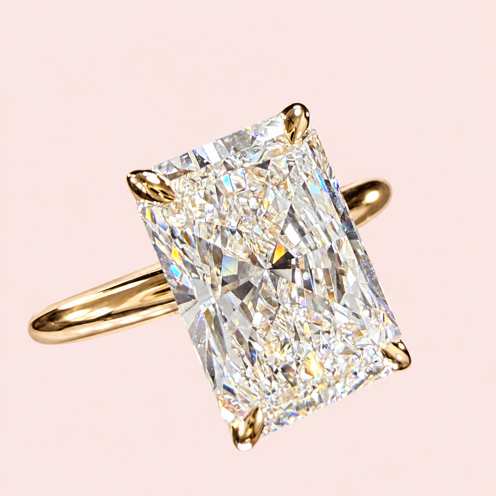 Angled front view of a radiant-cut diamond solitaire with four yellow-gold prongs and a polished plain band.