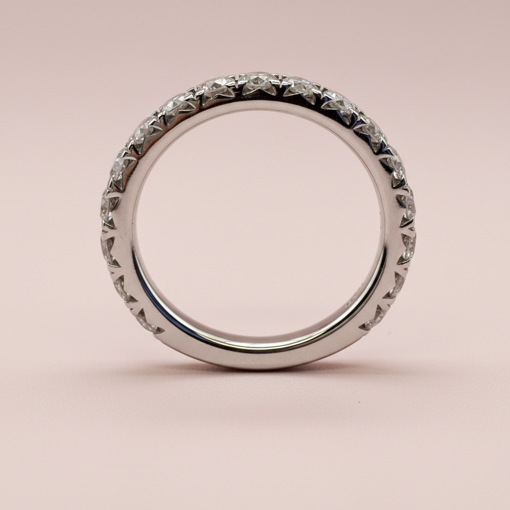 Upright side profile of a white-gold diamond wedding band showing the stone settings and polished interior.