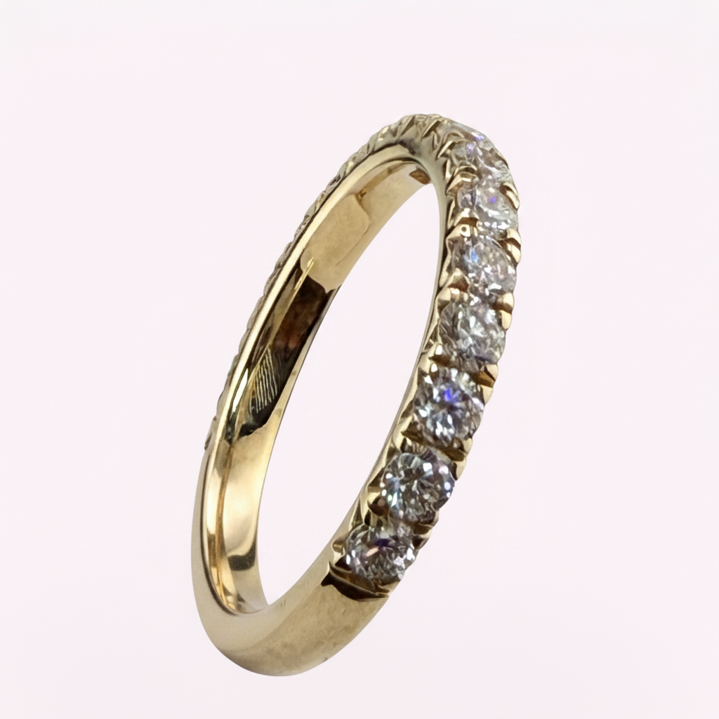 14K yellow gold 2.5mm French pavé round diamond wedding band on pale pink background