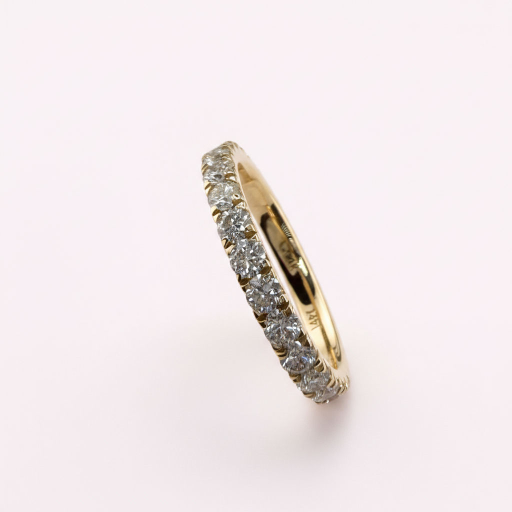 14K yellow gold 2.5mm French pavé round diamond wedding band on pale pink background