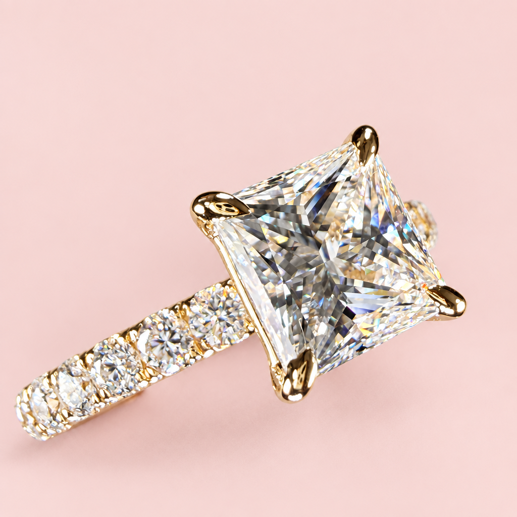 Opposite angled view of a princess-cut diamond engagement ring showing yellow-gold corner prongs and a pavé band.