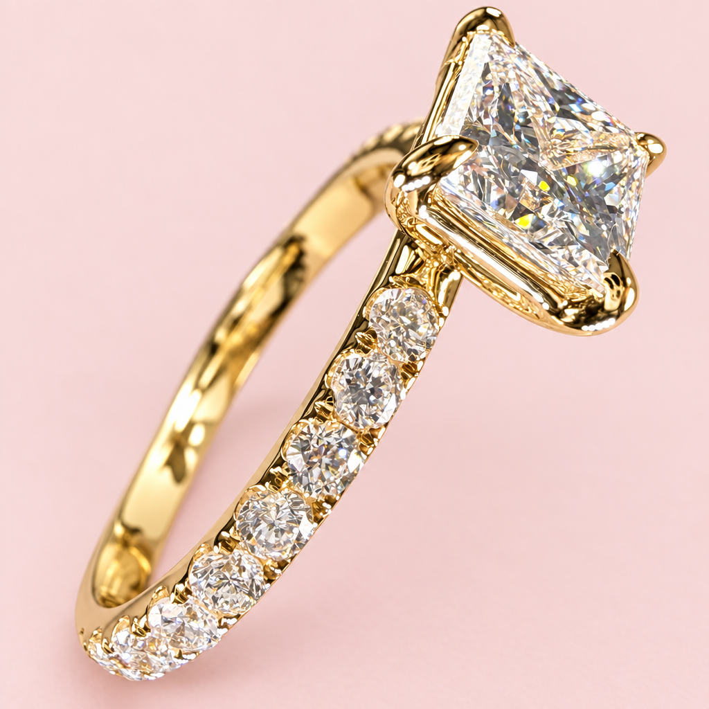 Close side angle of a princess-cut diamond ring showing yellow-gold corner prongs and a diamond-set shoulder.
