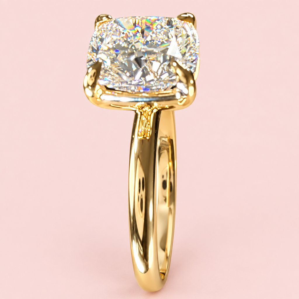 End-on view of a cushion-cut diamond solitaire showing yellow-gold prongs and a polished plain band.